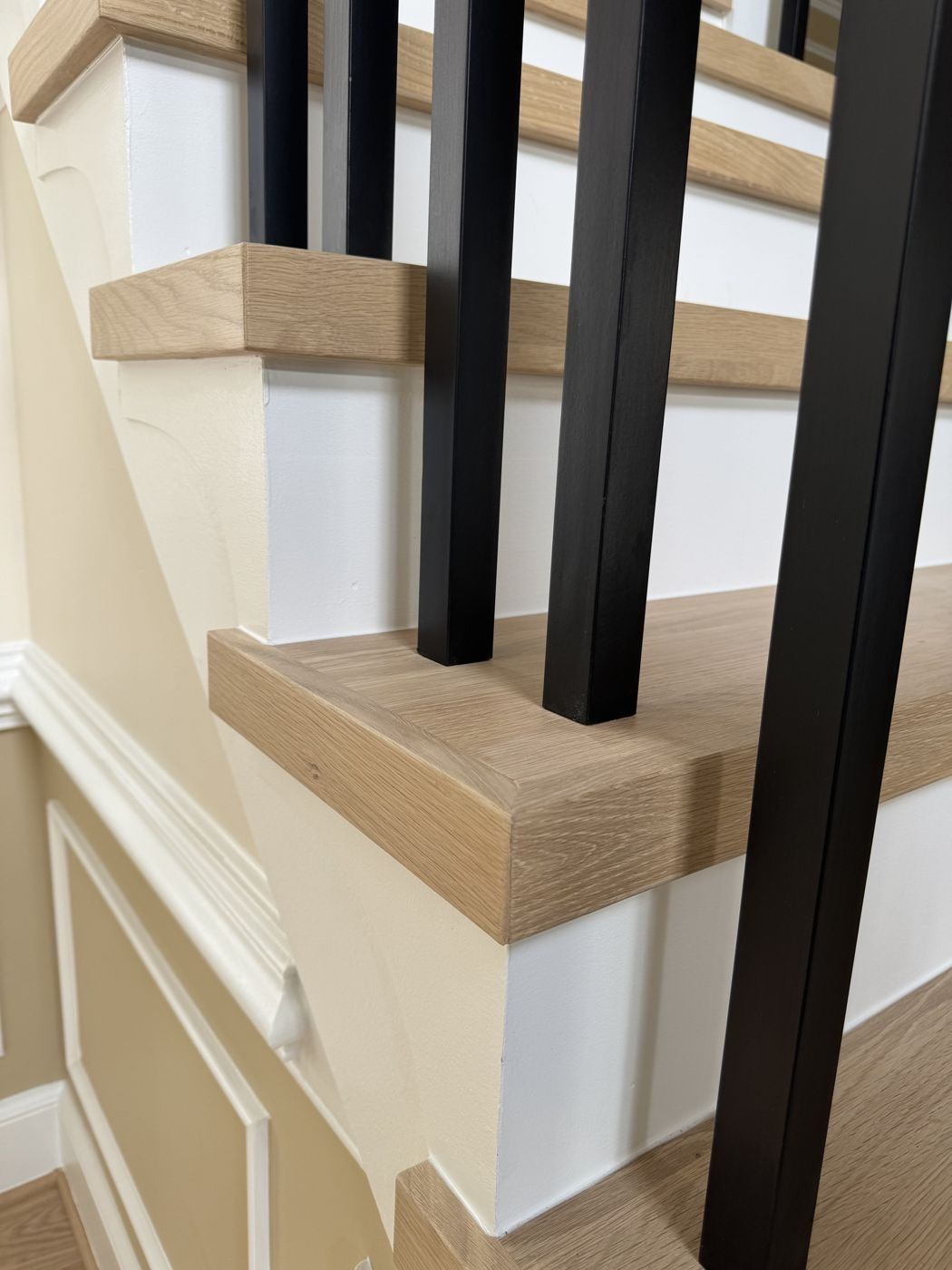 After close-up: square-edge white oak tread with black balusters