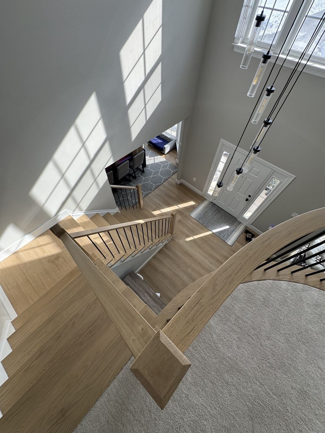 Looking down from a curved white oak landing into a foyer