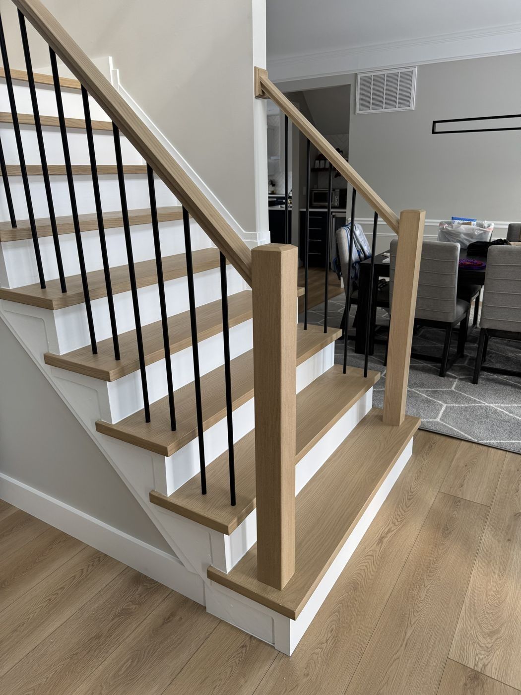 White oak stair with black balusters beside a dining room
