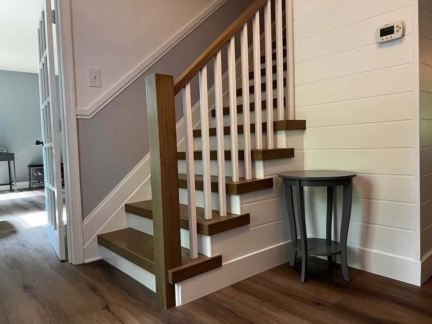 Oak treads and white balusters beside a shiplap wall