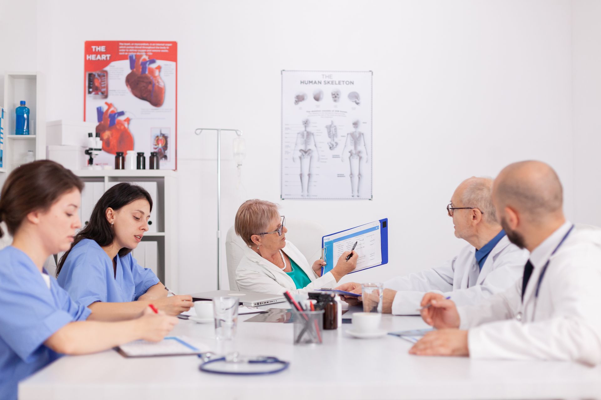 Medical team in meeting with patient, reviewing documents. Clinic room setting.