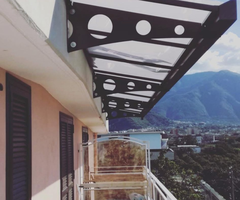 Balcone con tenda da sole moderna e trasparente e vista sulla città e sulle montagne.