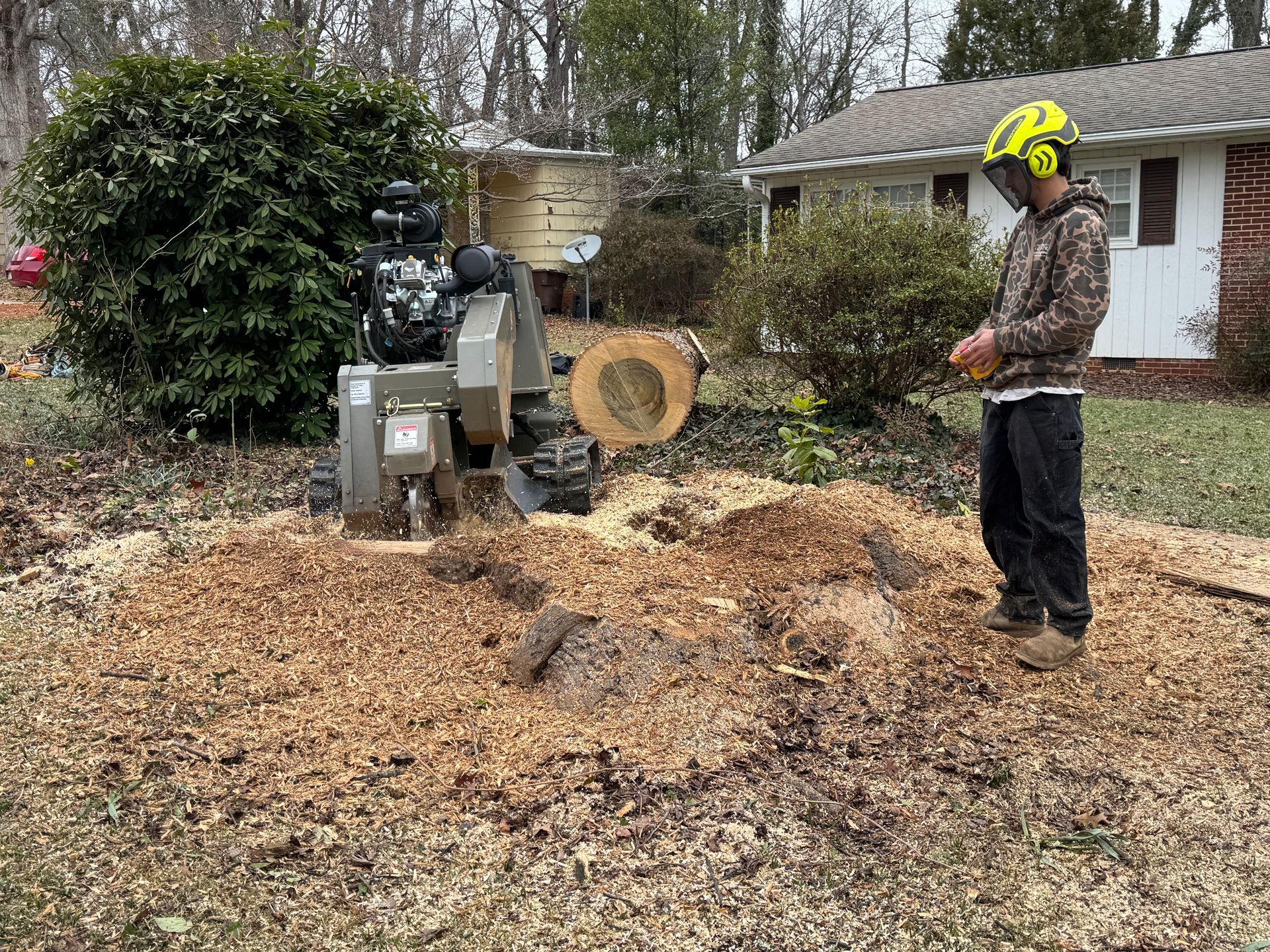 Worker using a wood chipper on a pile of branches in a suburban yard