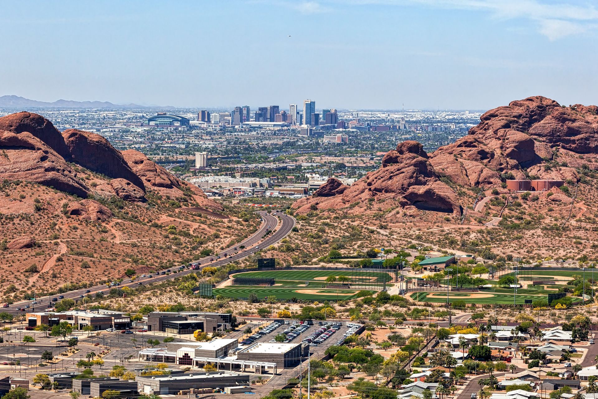 Desert city skyline framed by red rock mountains under a clear blue sky