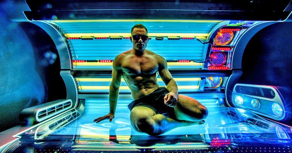 Eim muskulöser Mann mit nacktem Oberkörper sitz auf einem Solarium.