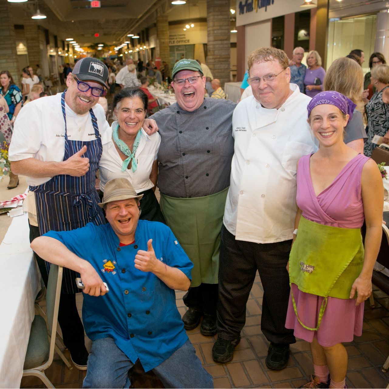 Chefs, smiling and posing, indoors, with tables and people in the background. Bounty on the Bricks, Athens County, OH