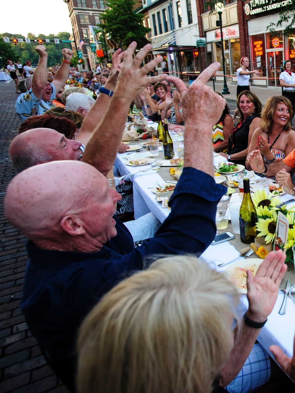 A group of people sitting at a table with their hands in the air