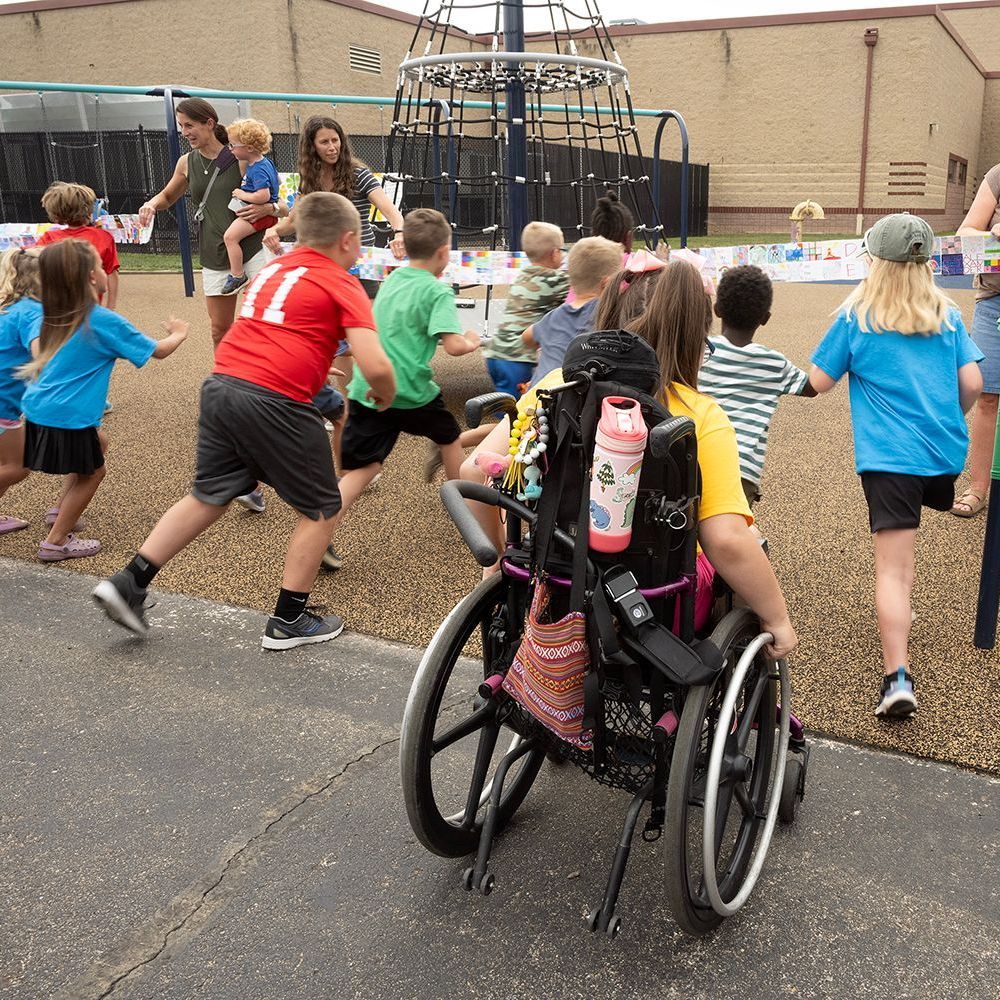 Children playing at a playground, one in a wheelchair.