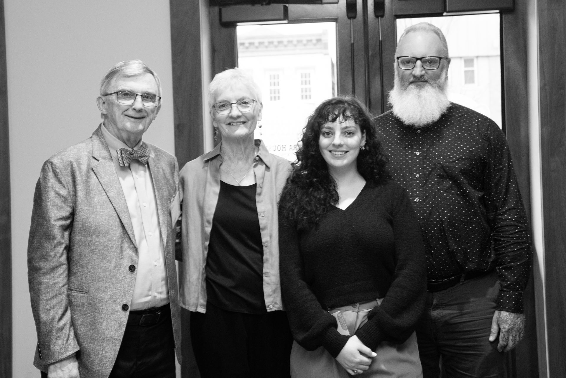 Four people in a doorway: two older, two younger. All are smiling and looking at the camera.