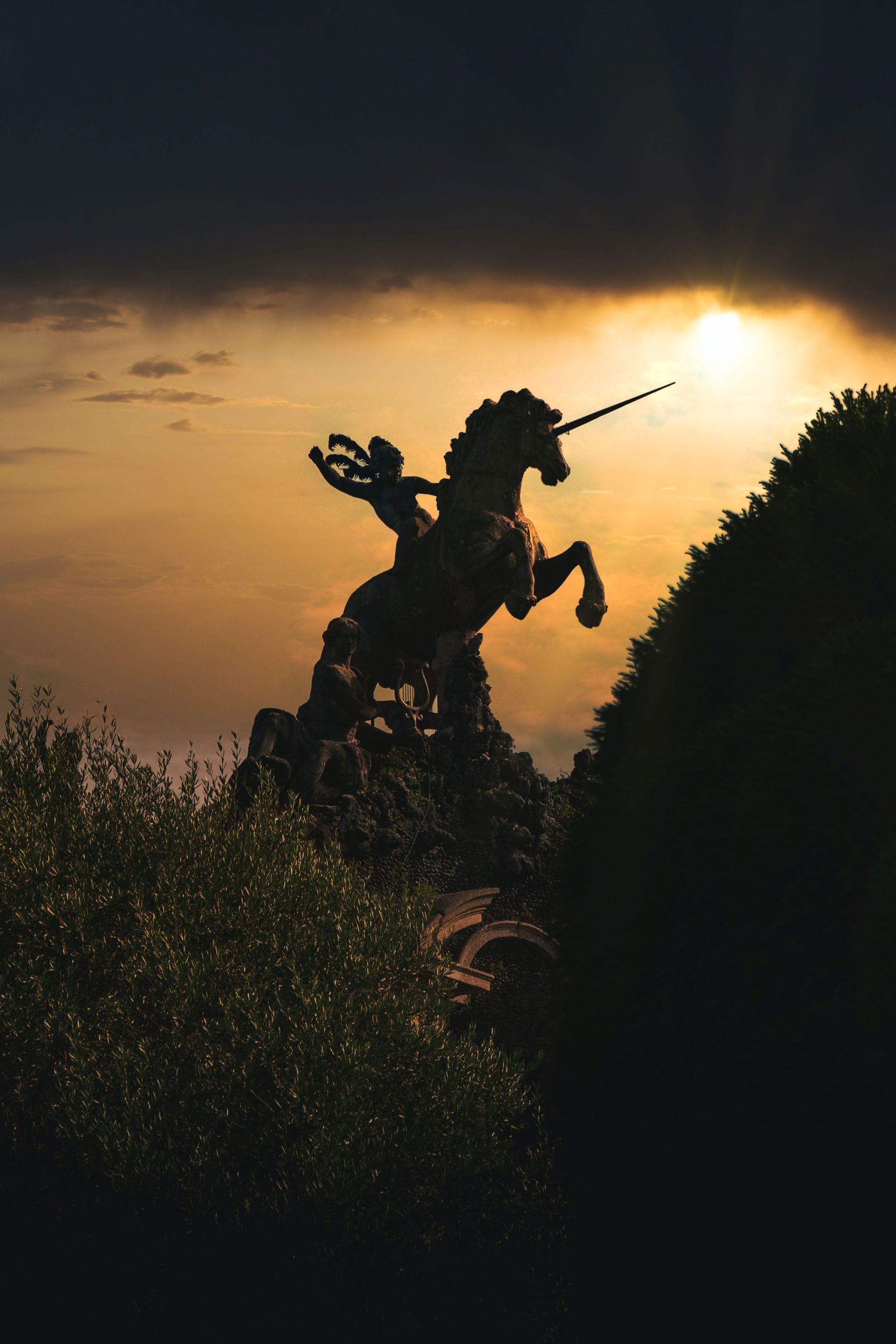 Silhouetted statue of a unicorn and rider against a golden sunset sky