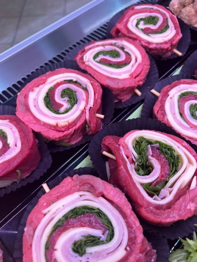 Involtini arrotolati rosa e bianchi con ripieno verde, disposti su un vassoio