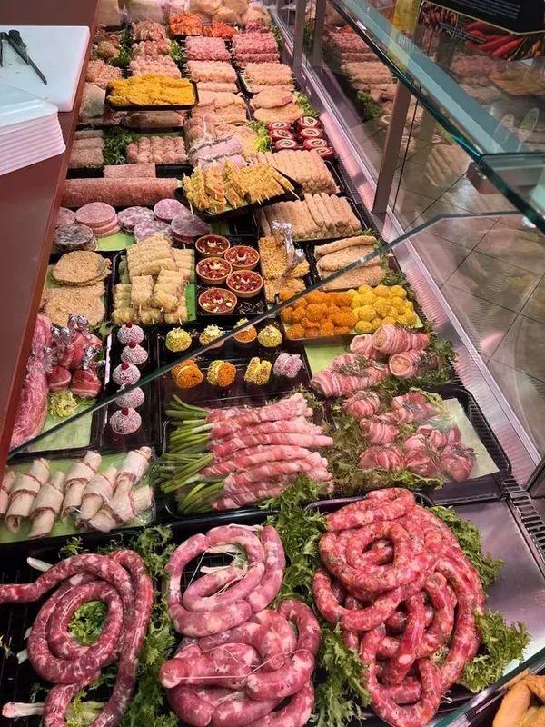 Assortimento di carni e salsicce disposto su vassoi al banco gastronomia.