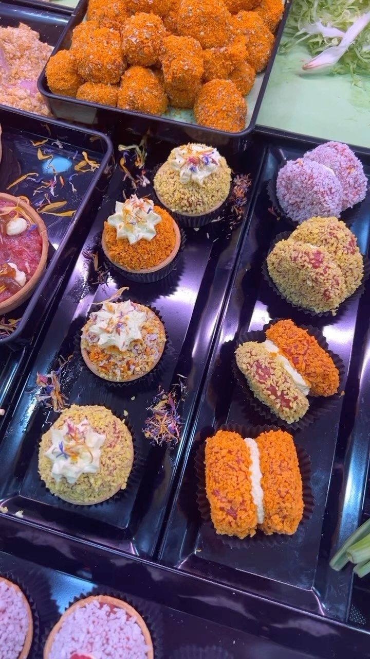 Assortimento di mochi e dolci di riso giapponesi colorati, disposti su vassoi neri in una vetrina.