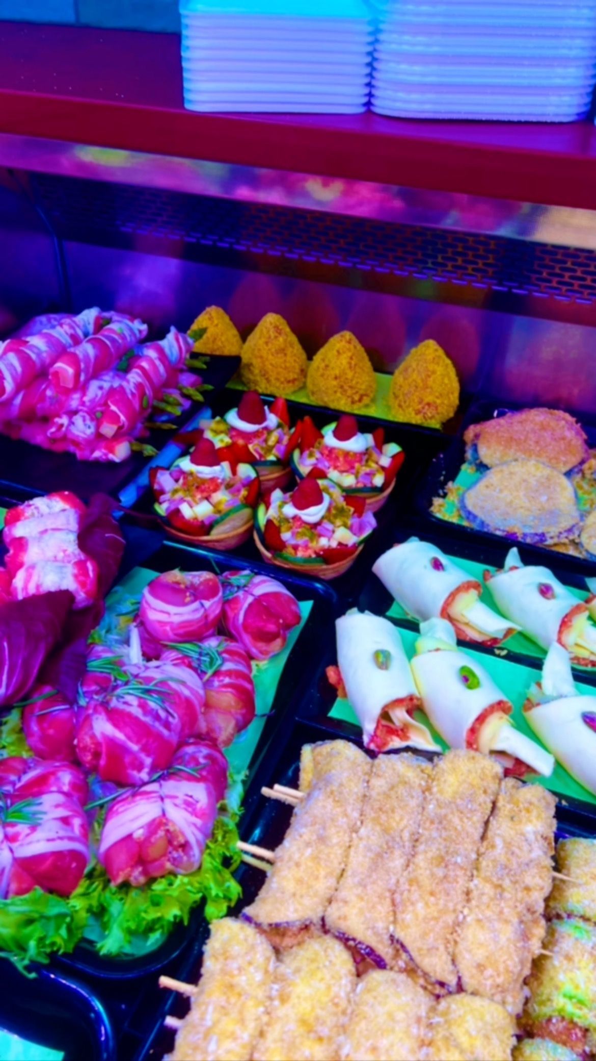 Assortimento di dolci tradizionali colorati, disposti in file su un vassoio da mercato o da pasticceria.