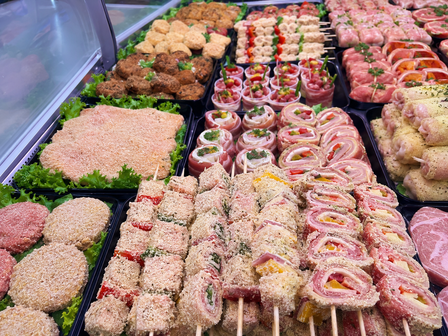Assortimento di rotoli e vassoi di sushi esposti in una vetrina refrigerata.