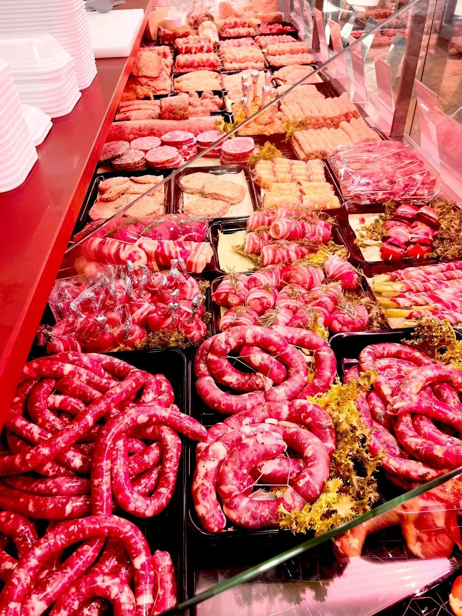 Esposizione di frutti di mare crudi assortiti su ghiaccio in un mercato, con gamberi rosa e polpi ben visibili.