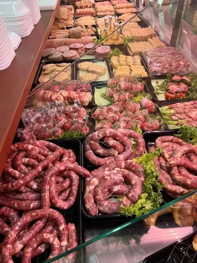 Vetrina di macelleria con un assortimento di salsicce e carni crude su un bancone di vetro.