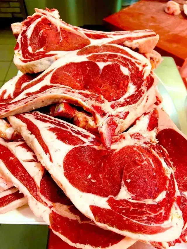 Pila di costolette di agnello crude marmorizzate su un vassoio
