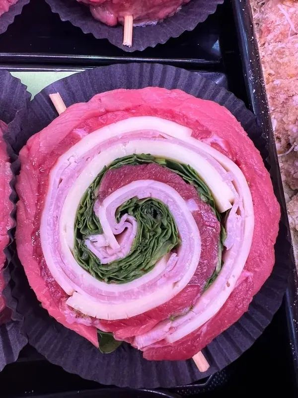 Dessert a spirale rosa in un bicchiere di carta nero, con ripieno verde e stuzzicadenti.