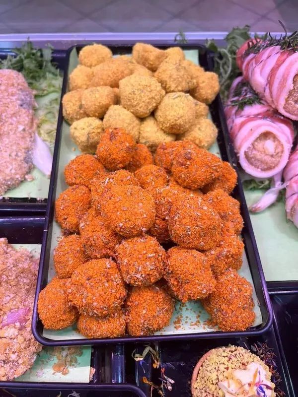 Vassoi di pasticcini ricoperti di sesamo e dolci colorati in una vetrina di una pasticceria.