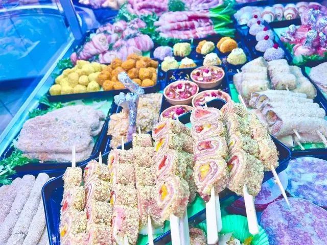 Una colorata esposizione di cibo di strada con dessert su spiedini e pasticcini assortiti in una bancarella del mercato.