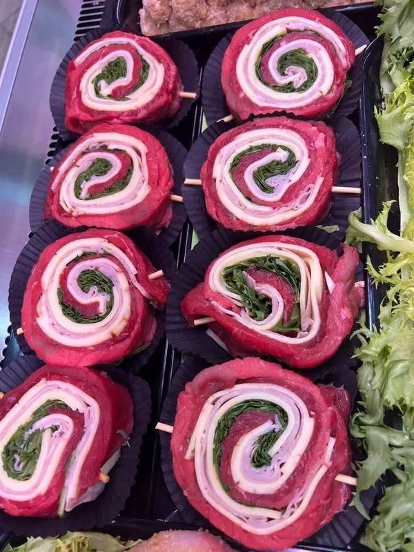Vassoio di girelle di barbabietola e formaggio con ripieno di erbe aromatiche e guarnizione di foglie.