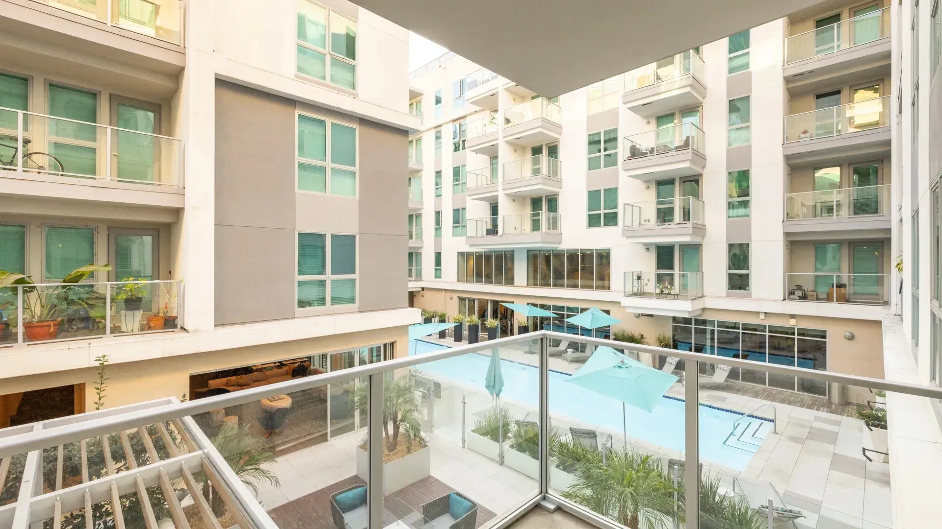 Modern apartment complex courtyard with a swimming pool and lounge chairs.