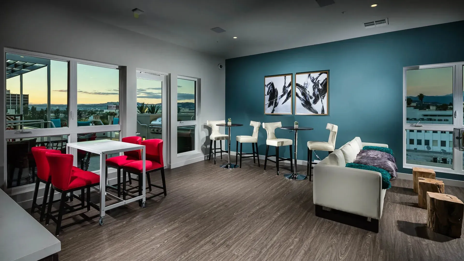 Community lounge area with seating, tables, and large windows with a city view.