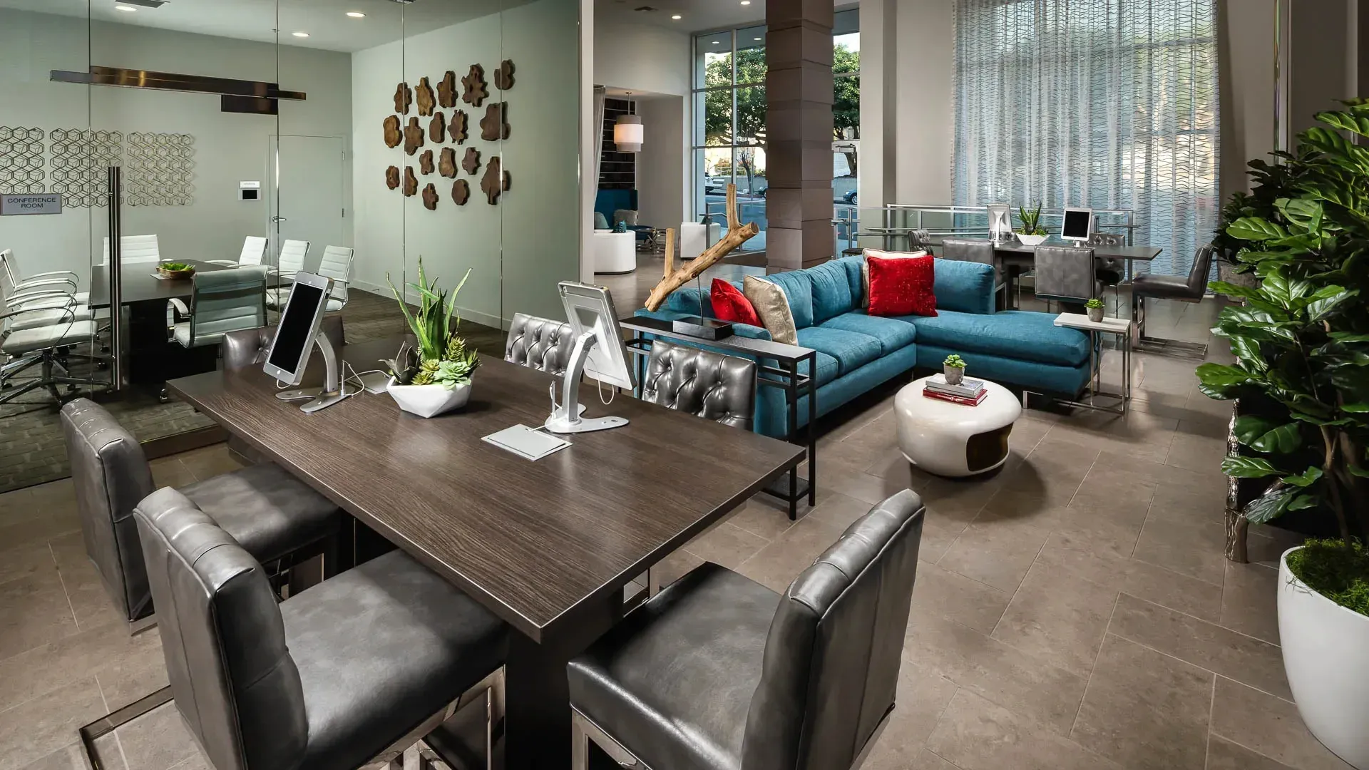 Modern co-working space with comfortable seating, conference table, and lush plants.