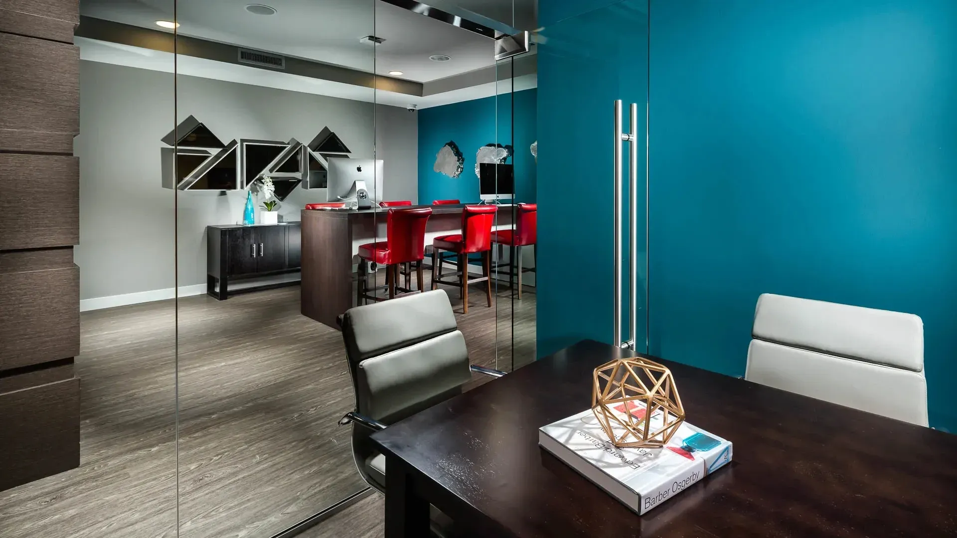 Modern leasing office with a conference table, chairs, and a reception area with bar stools.