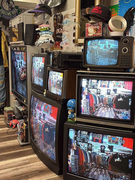 Stacked vintage CRT TVs displaying colorful scenes in a cluttered retro room