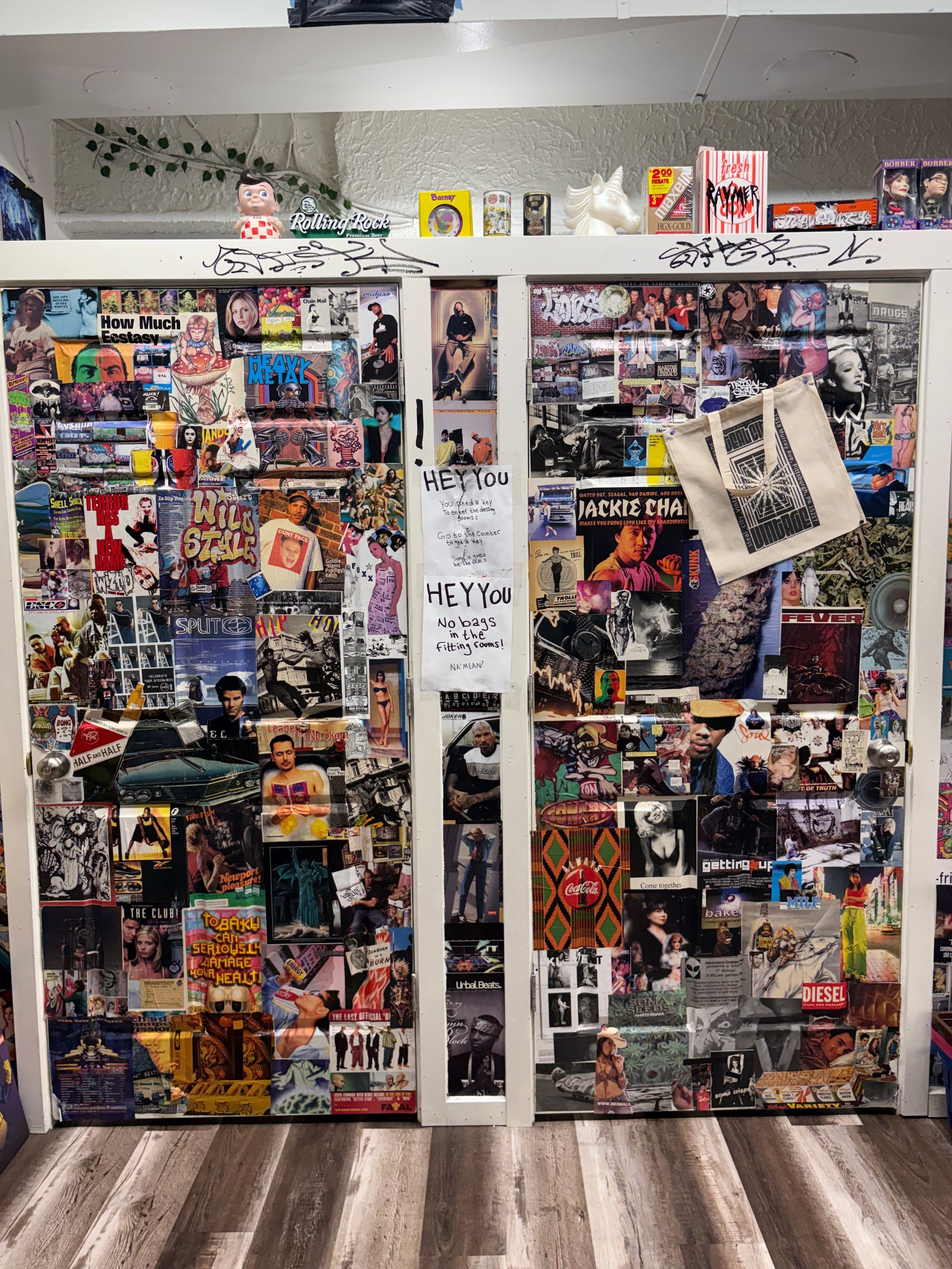 Two collage-covered doors with colorful posters and flyers, plus a hanging newspaper page in the center.