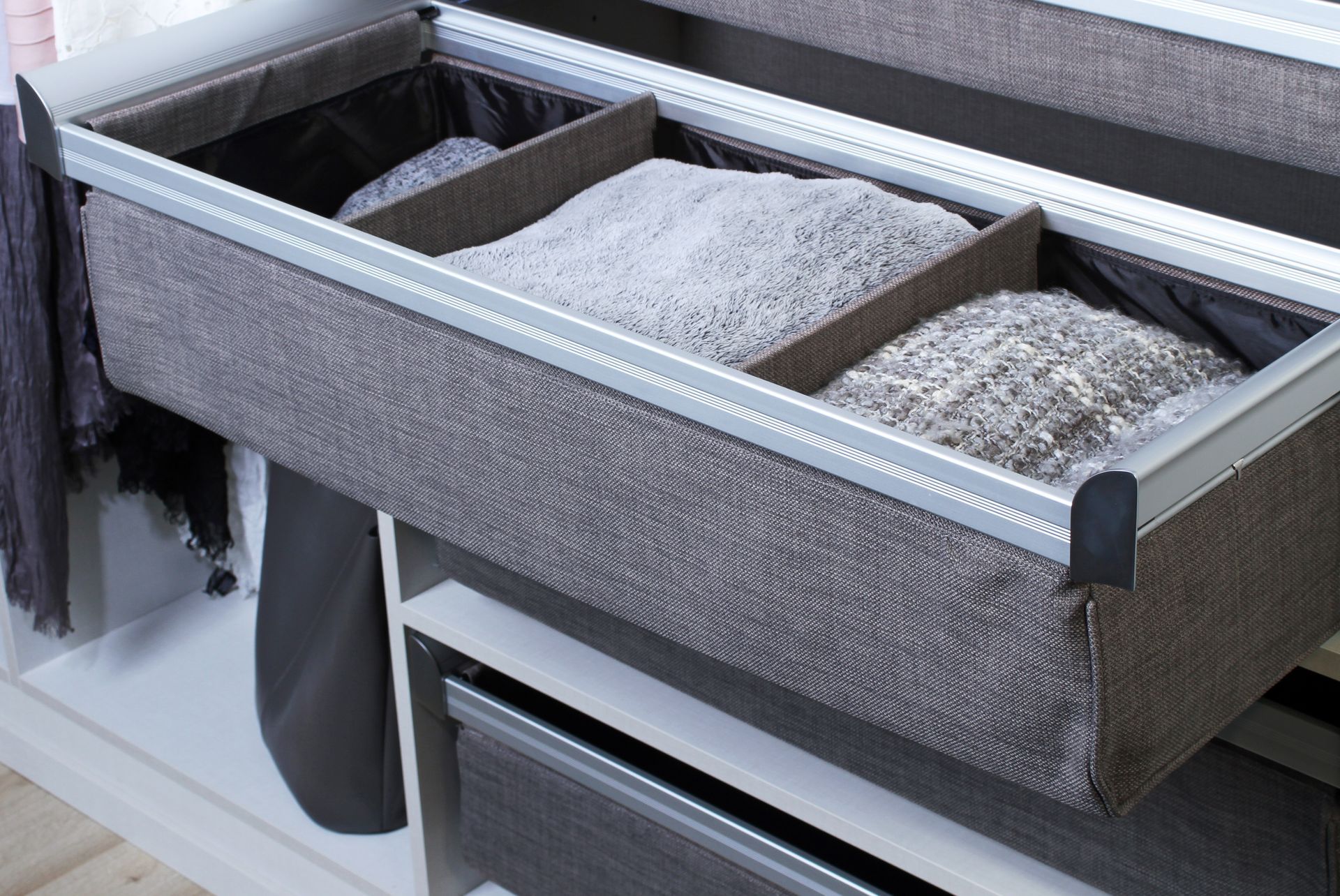 Gray closet drawer organizer with folded clothes and dividers on a shelf