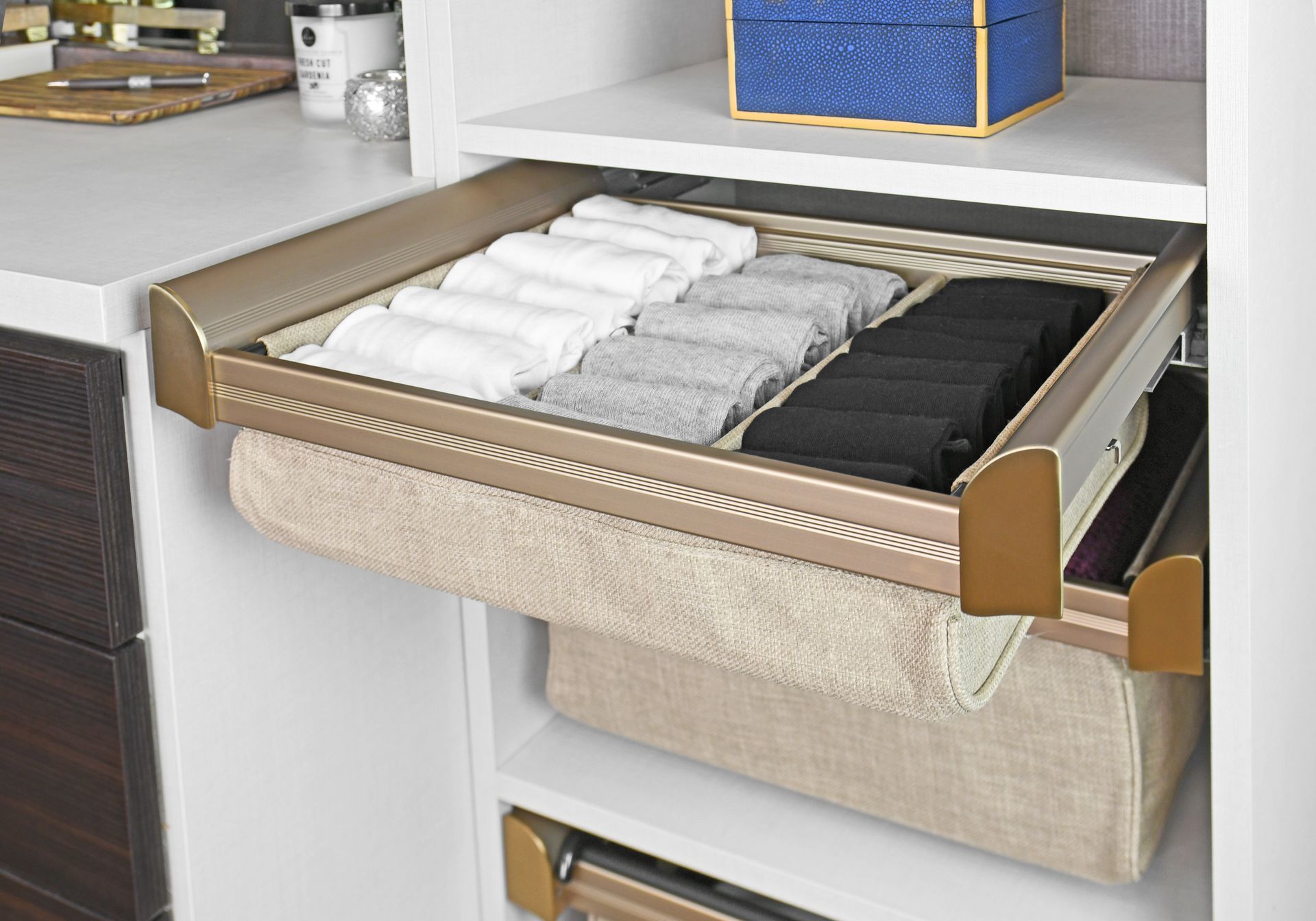 Closet drawer with neatly folded socks and a beige bin below.
