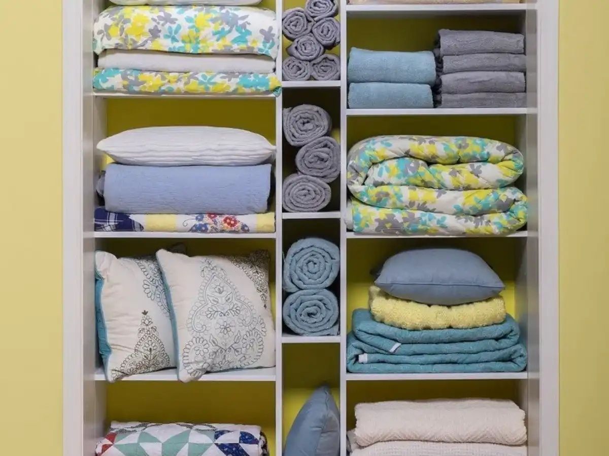 Gray walk-in closet with neatly organized clothing, including shirts, pants, and accessories. Neutral tones and a modern design are featured.