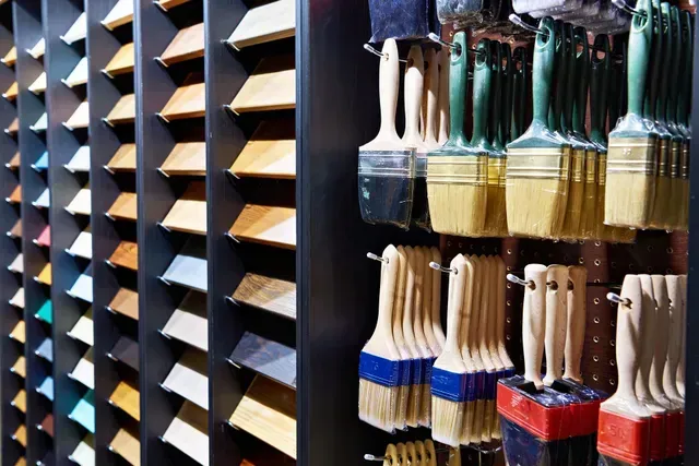 Paintbrushes hanging beside wood finish samples display in a hardware store. Paintbrushes hanging beside wood finish samples display in a hardware store.