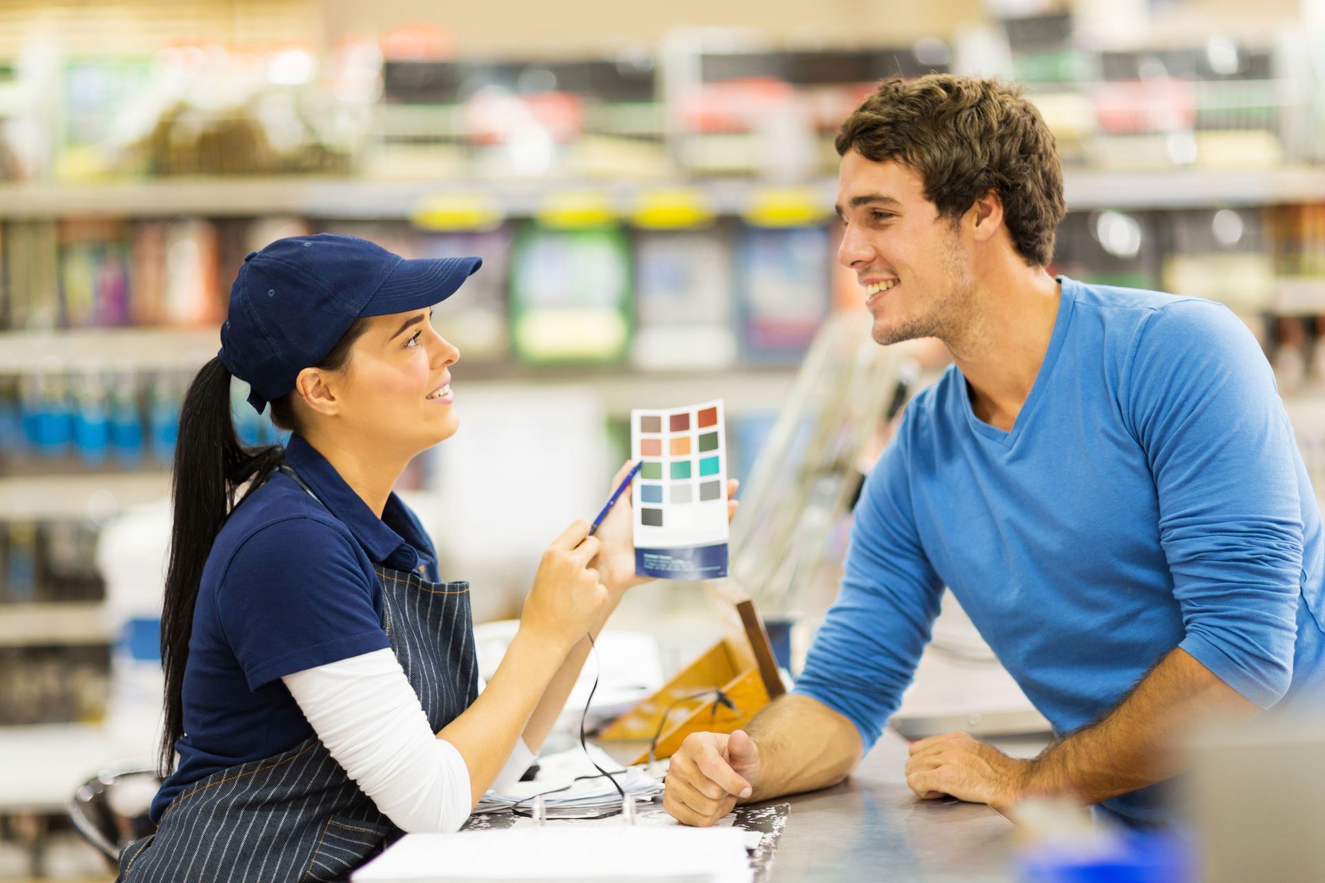 Store worker shows paint color samples to customer at home improvement counter