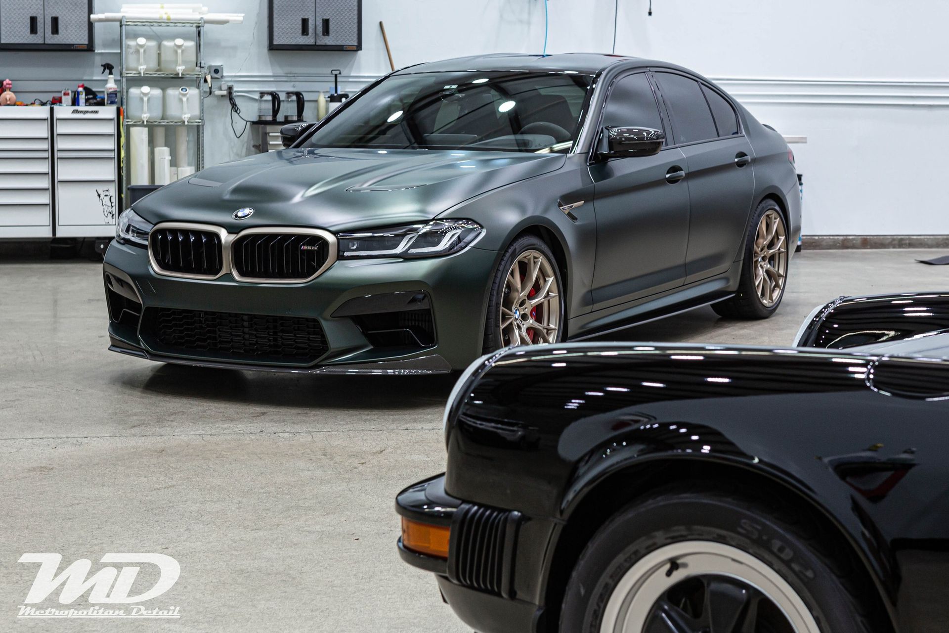 A bmw m5 is parked next to a black car in a garage.