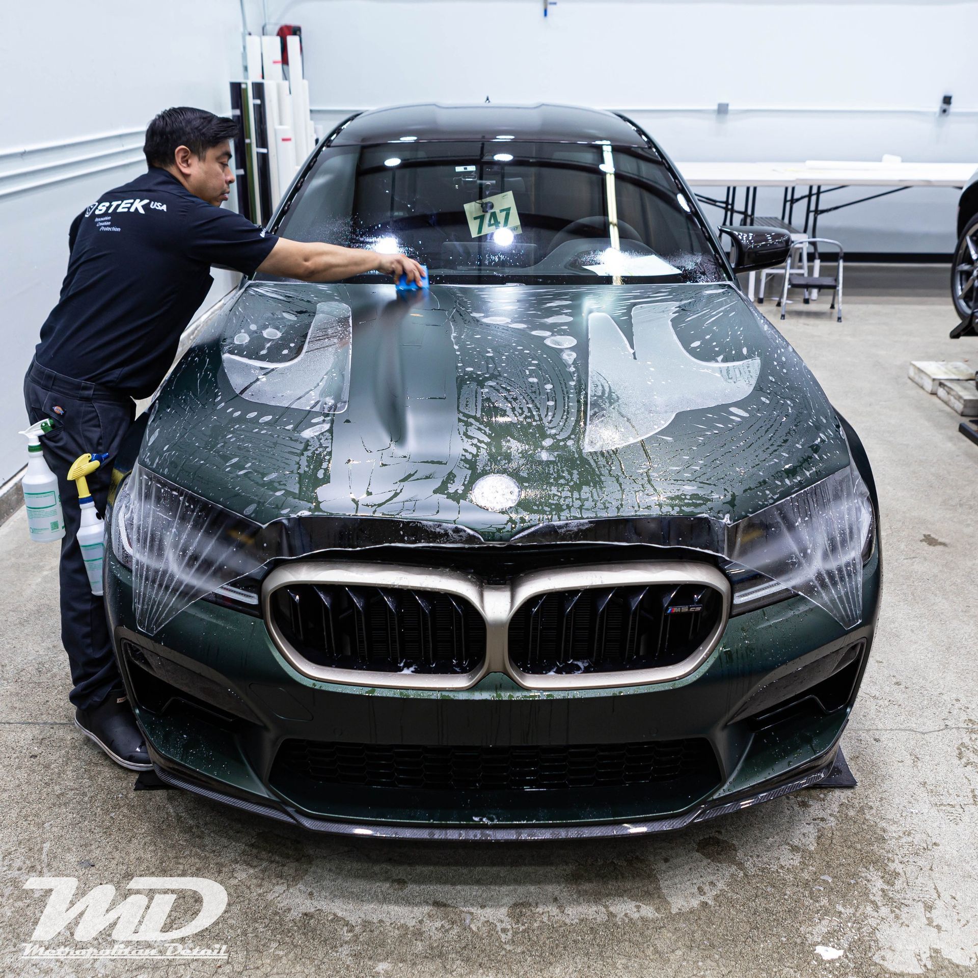 A man is cleaning the hood of a green car