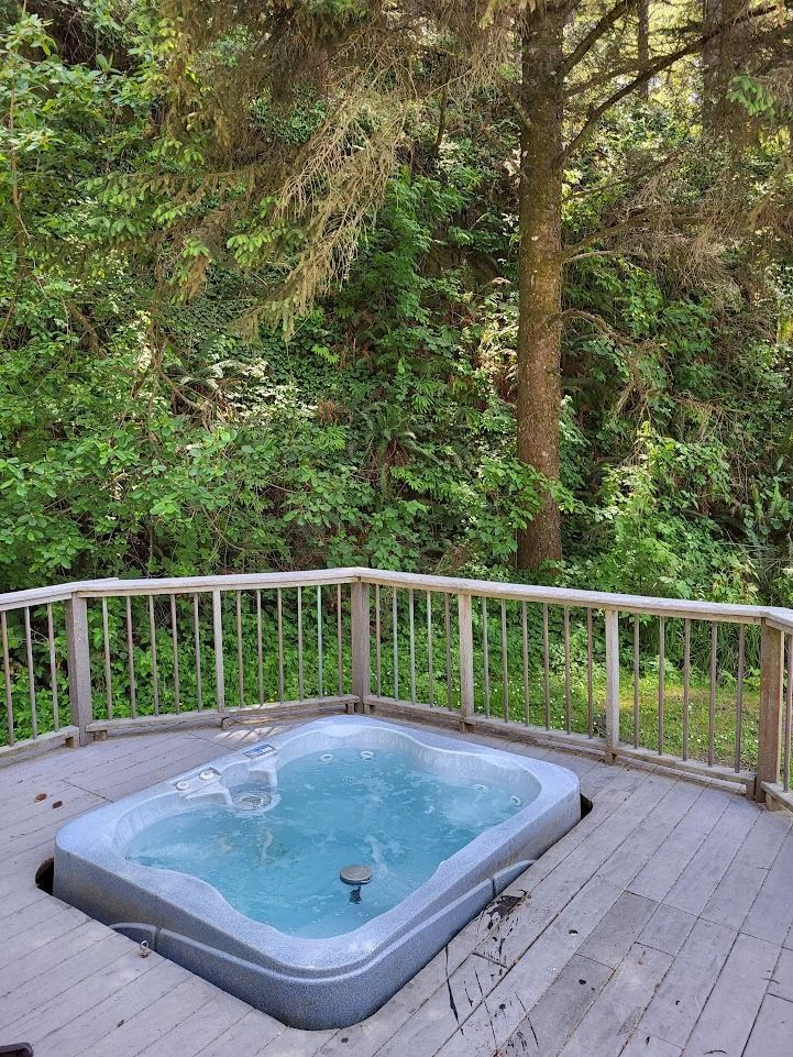 Wooden deck with a small hot tub overlooking a lush green forest