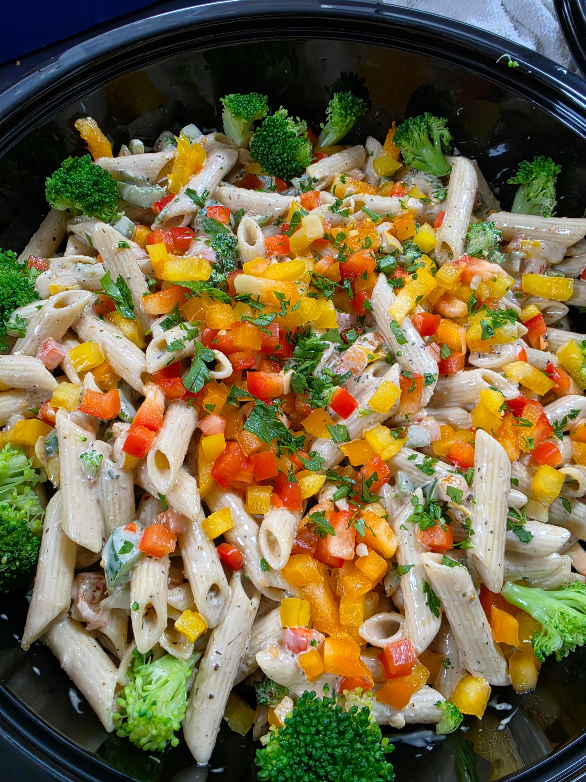 Bowl of pasta with broccoli, corn, diced vegetables, and herbs on top