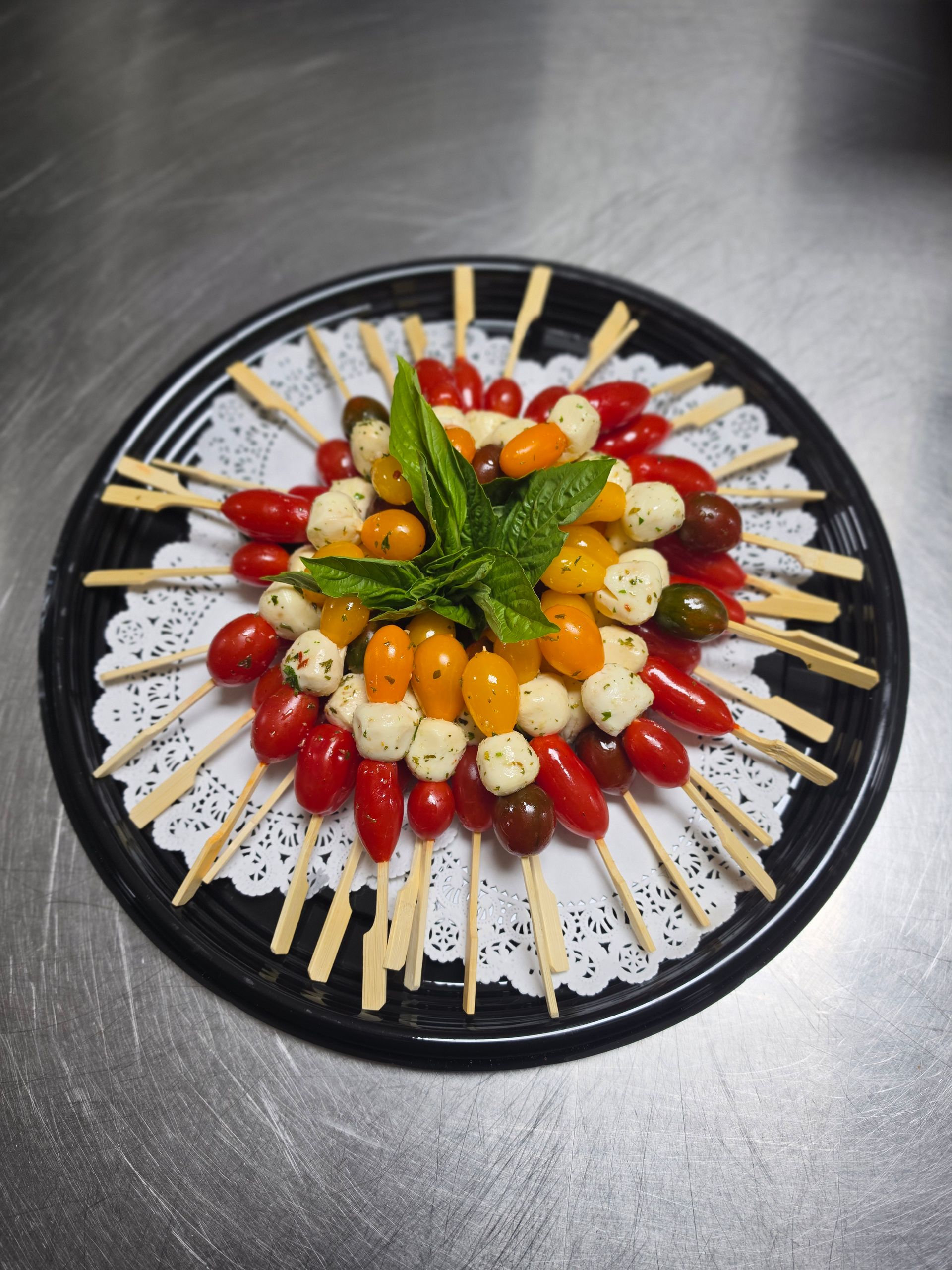 Colorful fruit-topped dessert arranged in a circle on a black platter, with mint garnish in the center