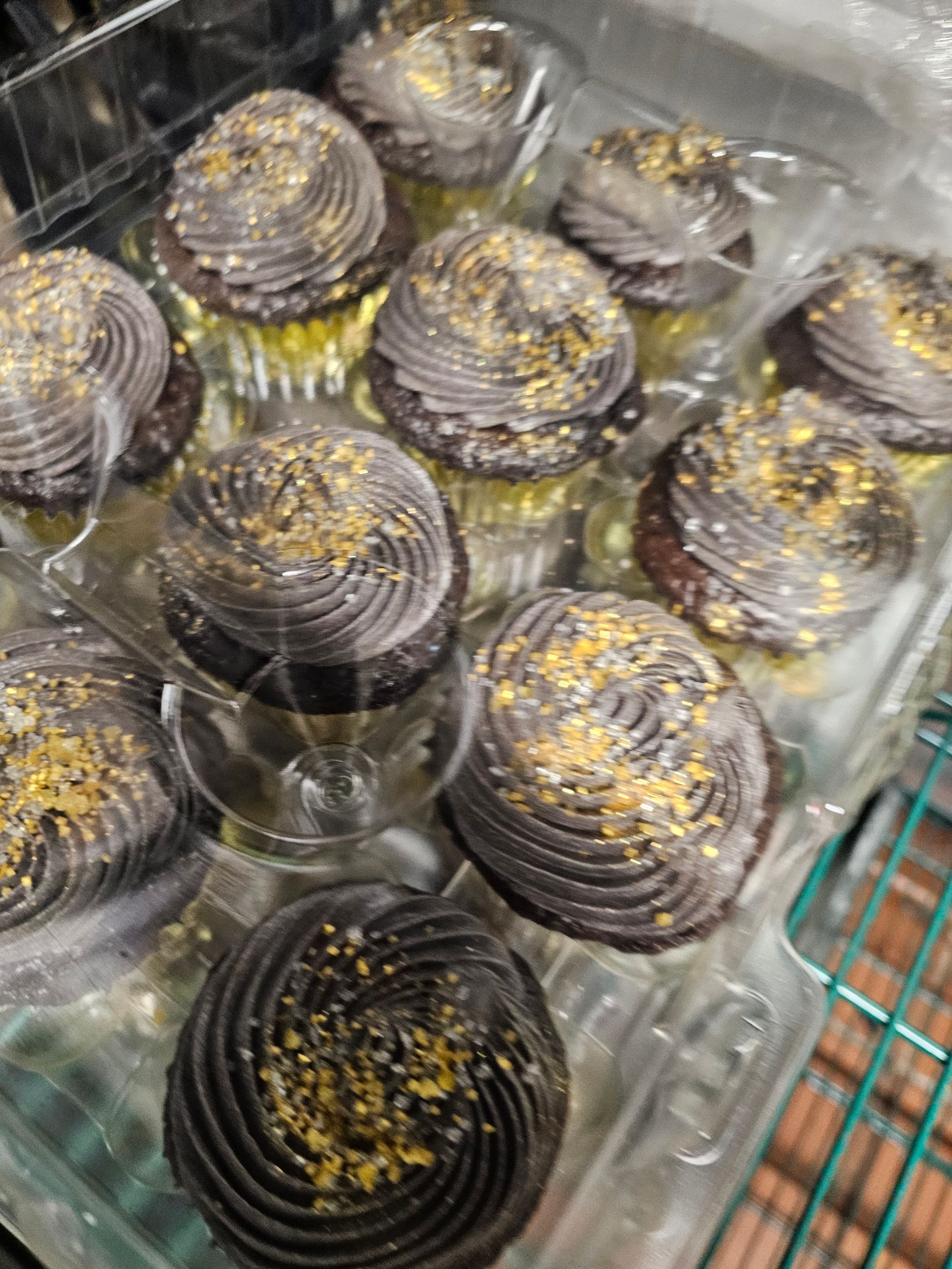 Clear plastic containers filled with dark round dessert cups topped with yellow sprinkles