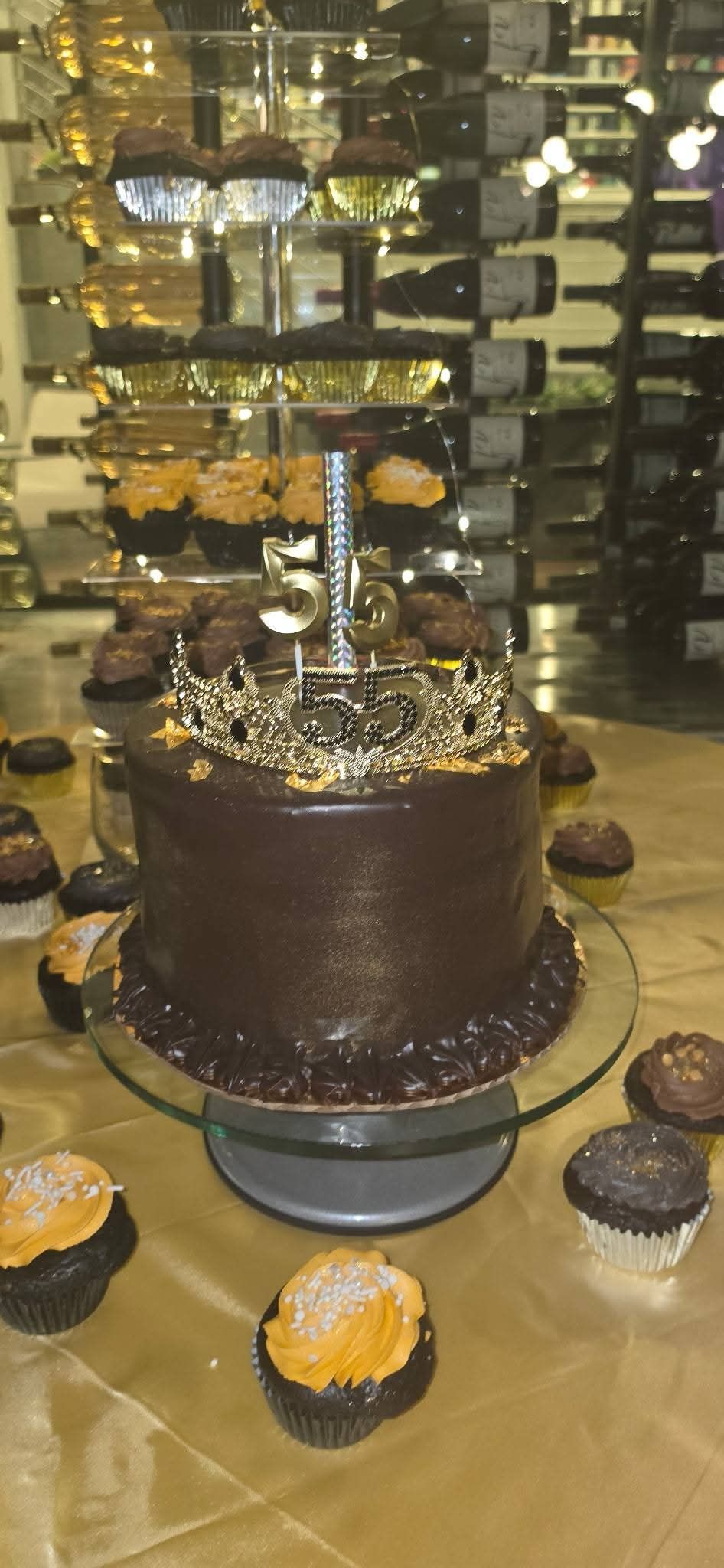 Chocolate cake display with cupcakes on a table in a bakery or café setting