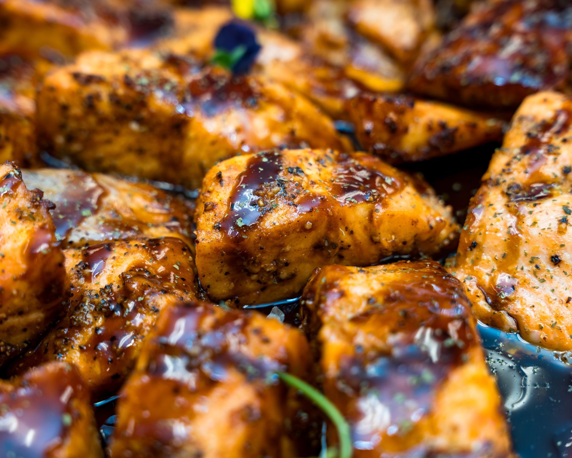 Close-up of glazed, charred grilled chicken pieces with a golden-brown, smoky finish
