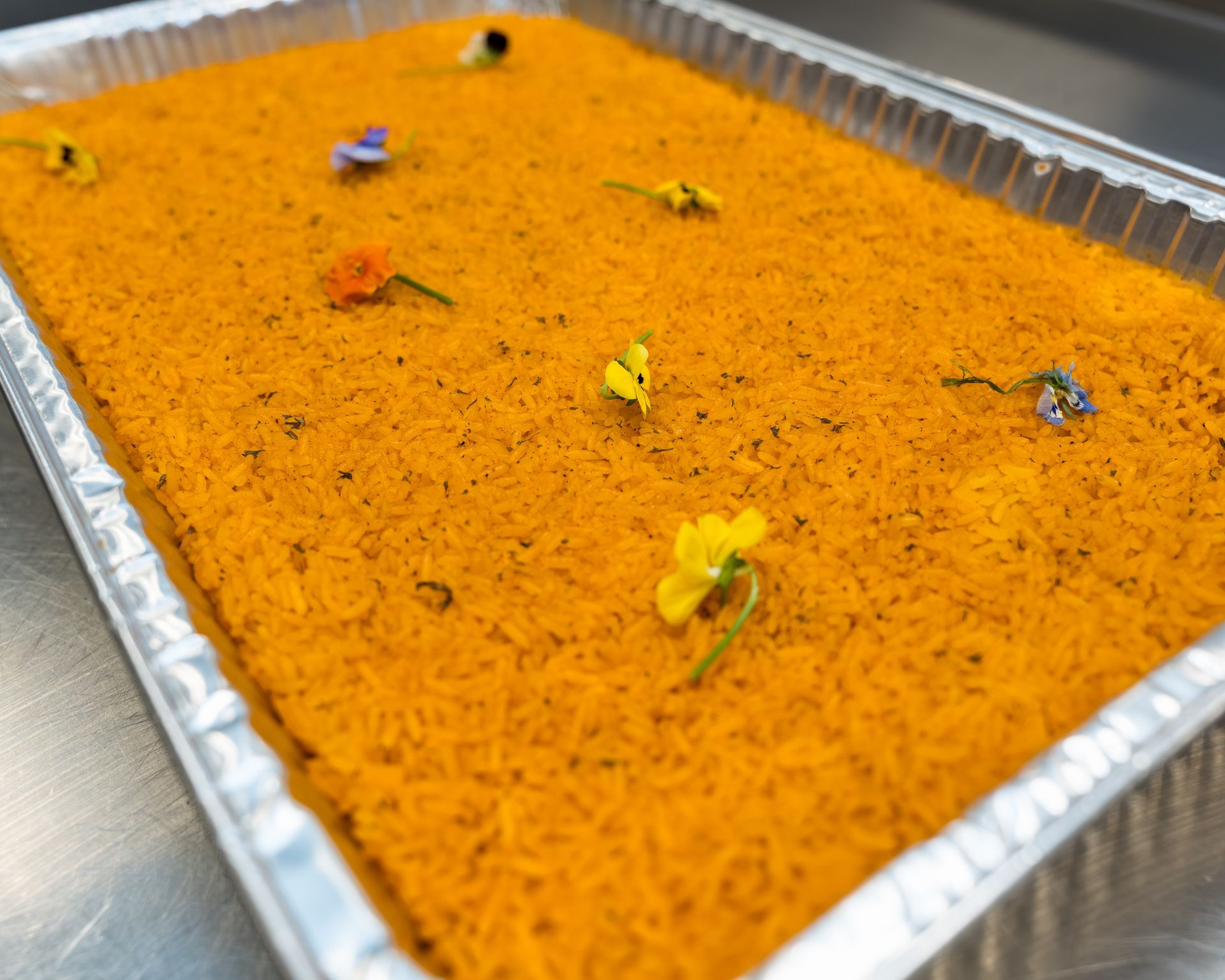 Tray of orange dessert topped with small edible flower petals
