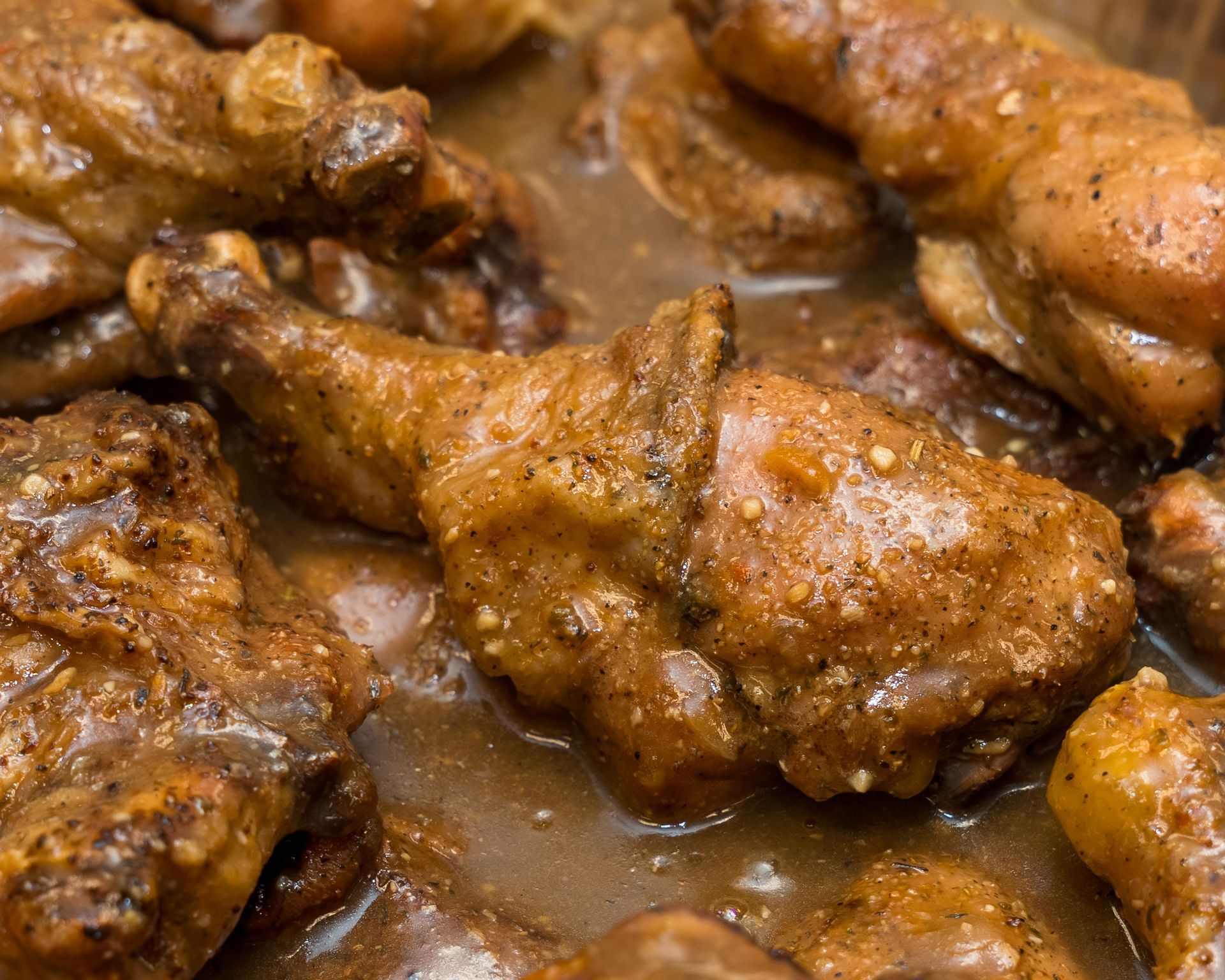 Glazed chicken drumsticks covered in brown sauce on a tray