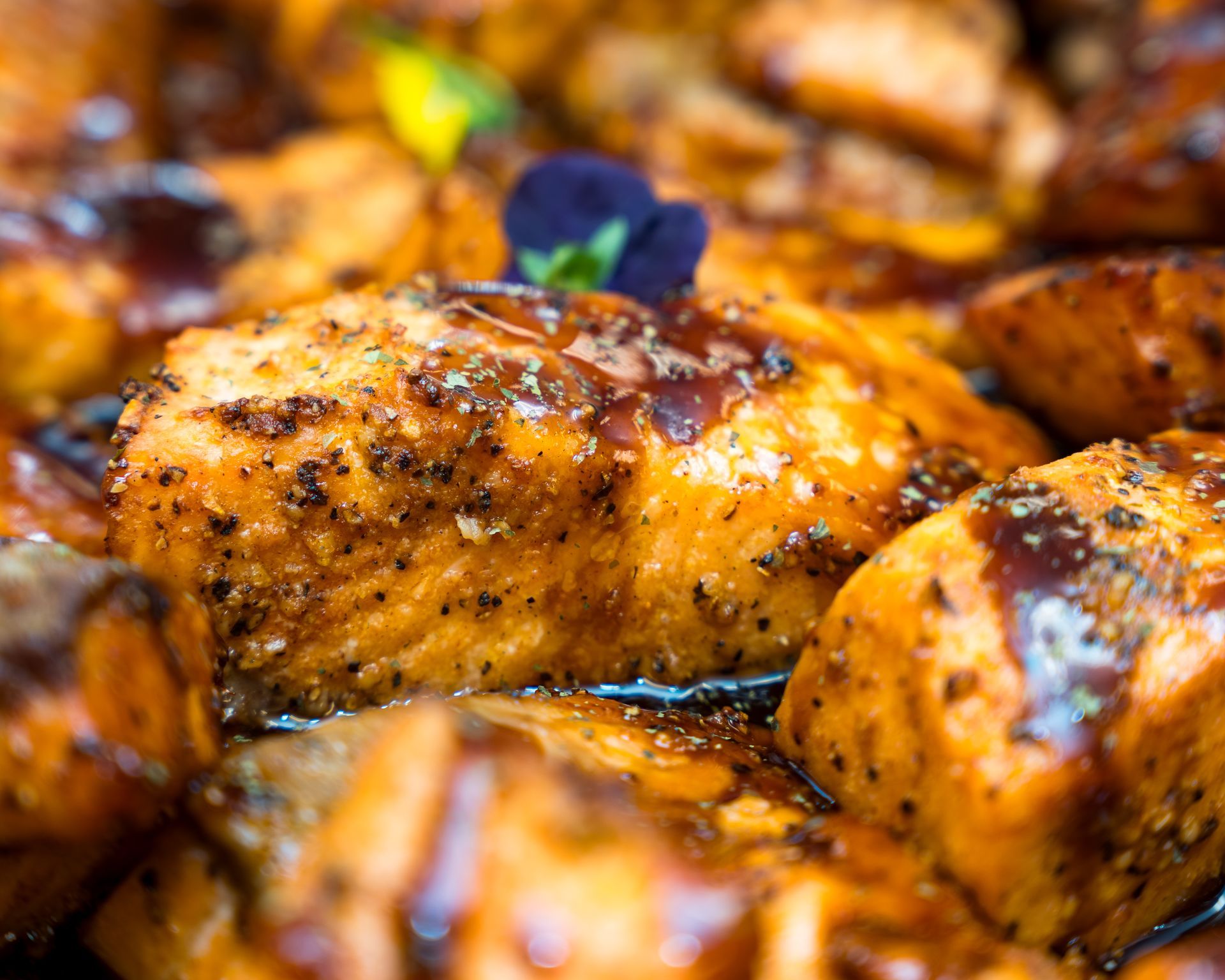 Close-up of golden-brown glazed roasted chicken pieces with herbs