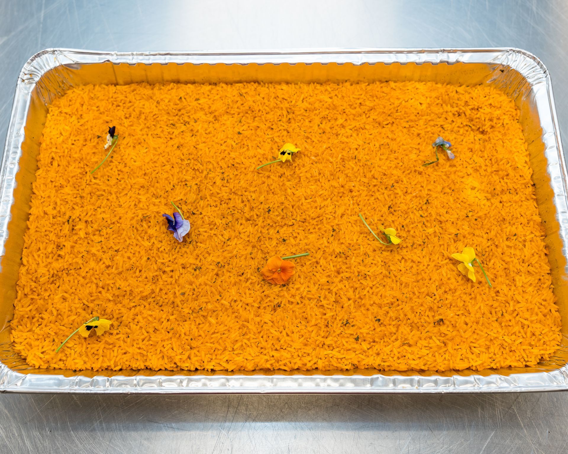 Tray of bright orange food with small colorful garnish pieces on top