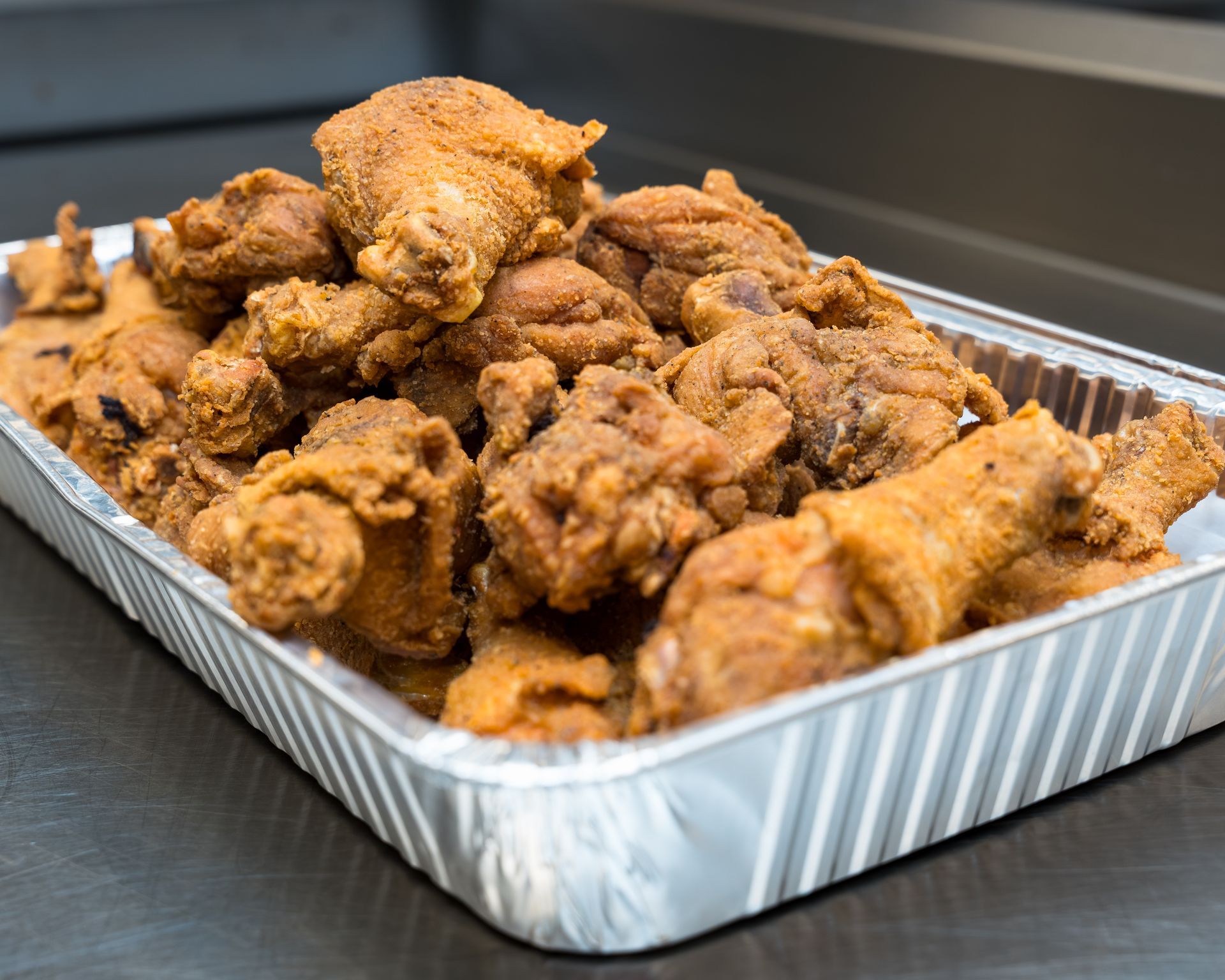 Tray of fried chicken pieces on a metal counter